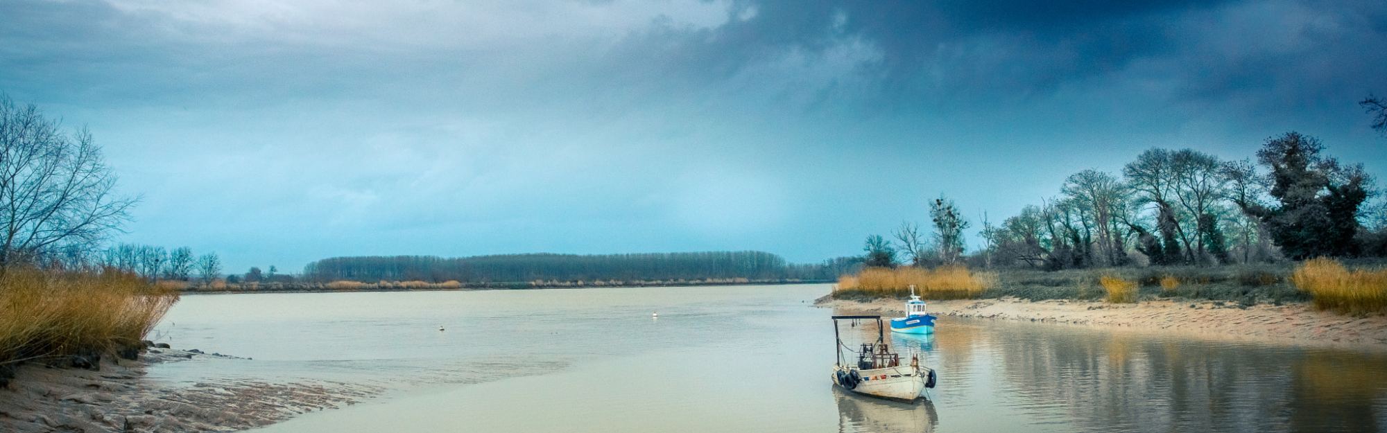 The lower Loire under a wide sky, pale shallow water running between low sandbanks with a single small boat on it.