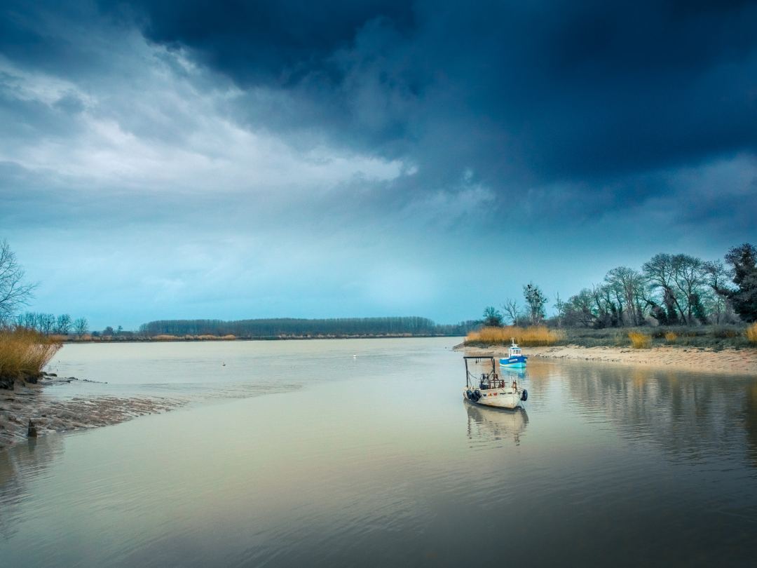The lower Loire under a wide sky, pale shallow water running between low sandbanks with a single small boat on it.
